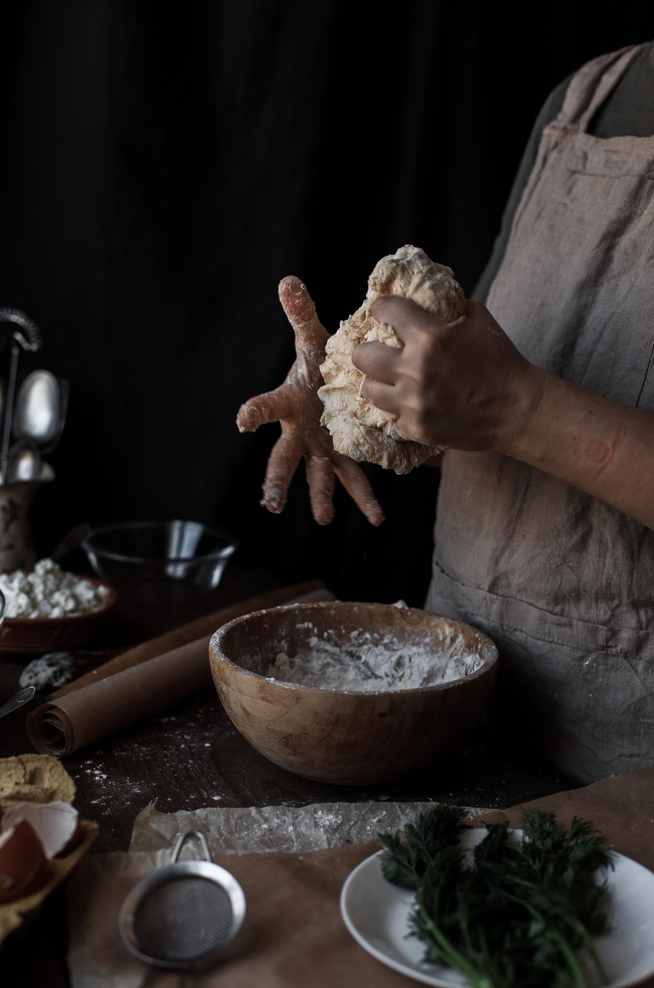 Instructor shaping dough in a warm studio kitchen